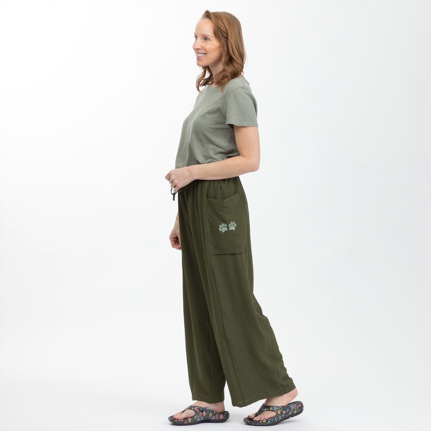 Woman wearing a green outfit with wide-leg pants on a white background