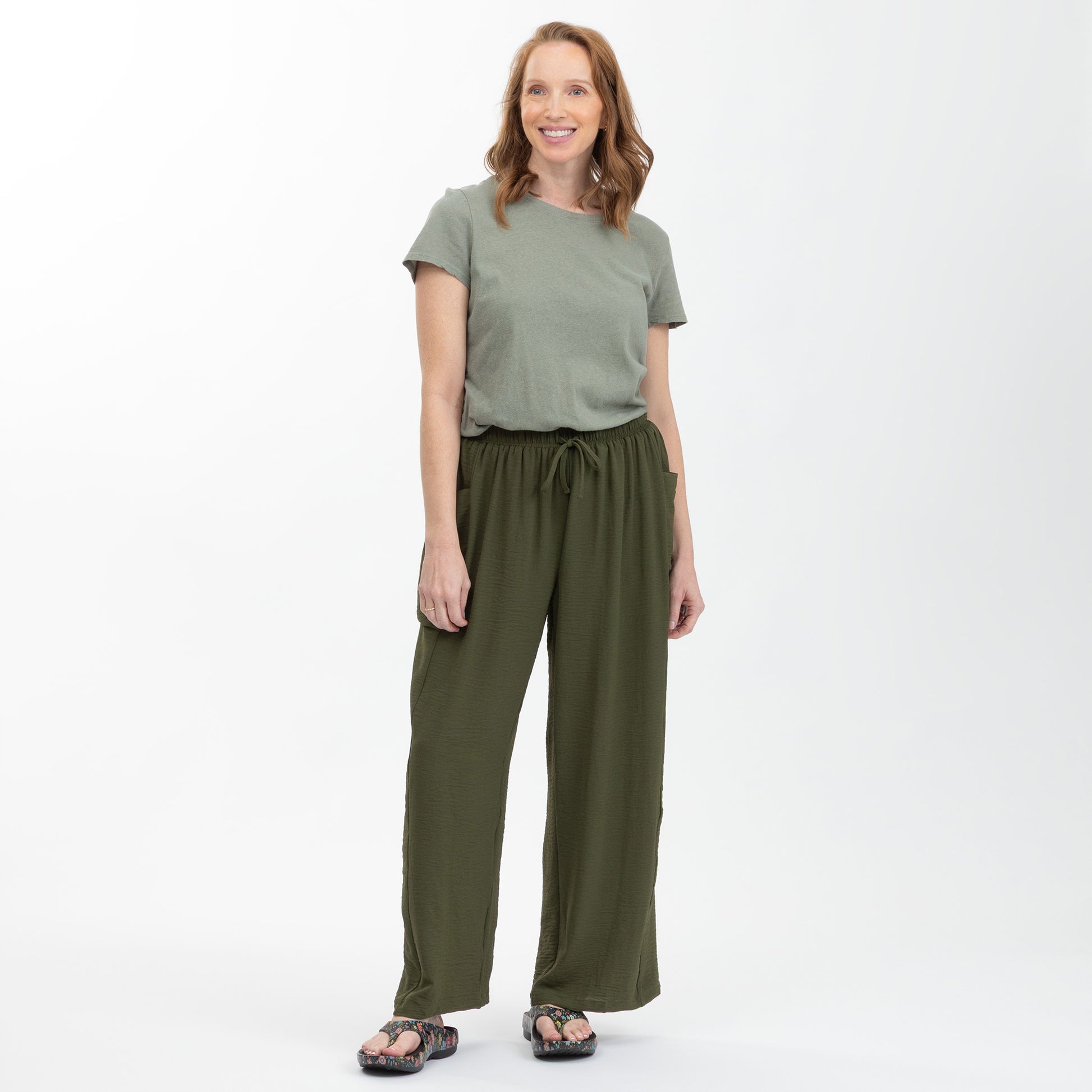 Woman wearing a green top and matching pants on a white background
