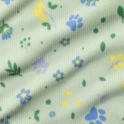 Fabric with small floral patterns and paws in blue, yellow, and green on a light green background