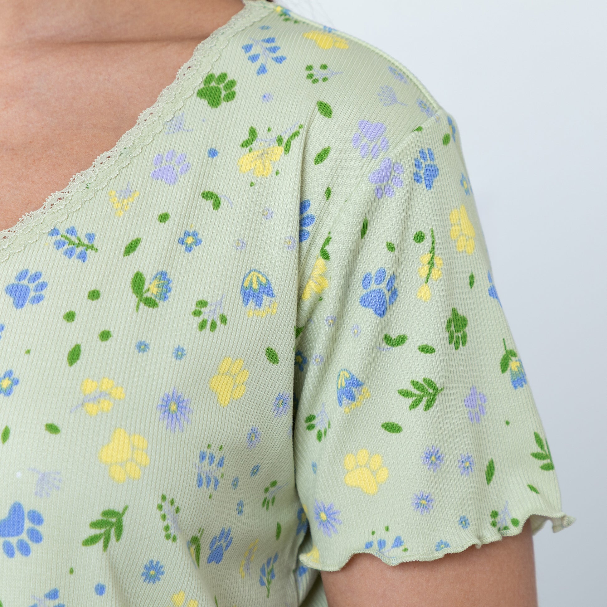 Light green v neck top with floral pattern on a plain background