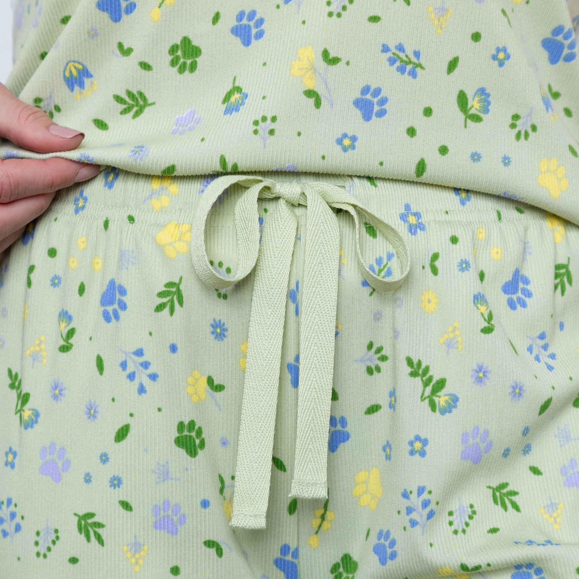 Light green fabric with floral pattern held by a hand