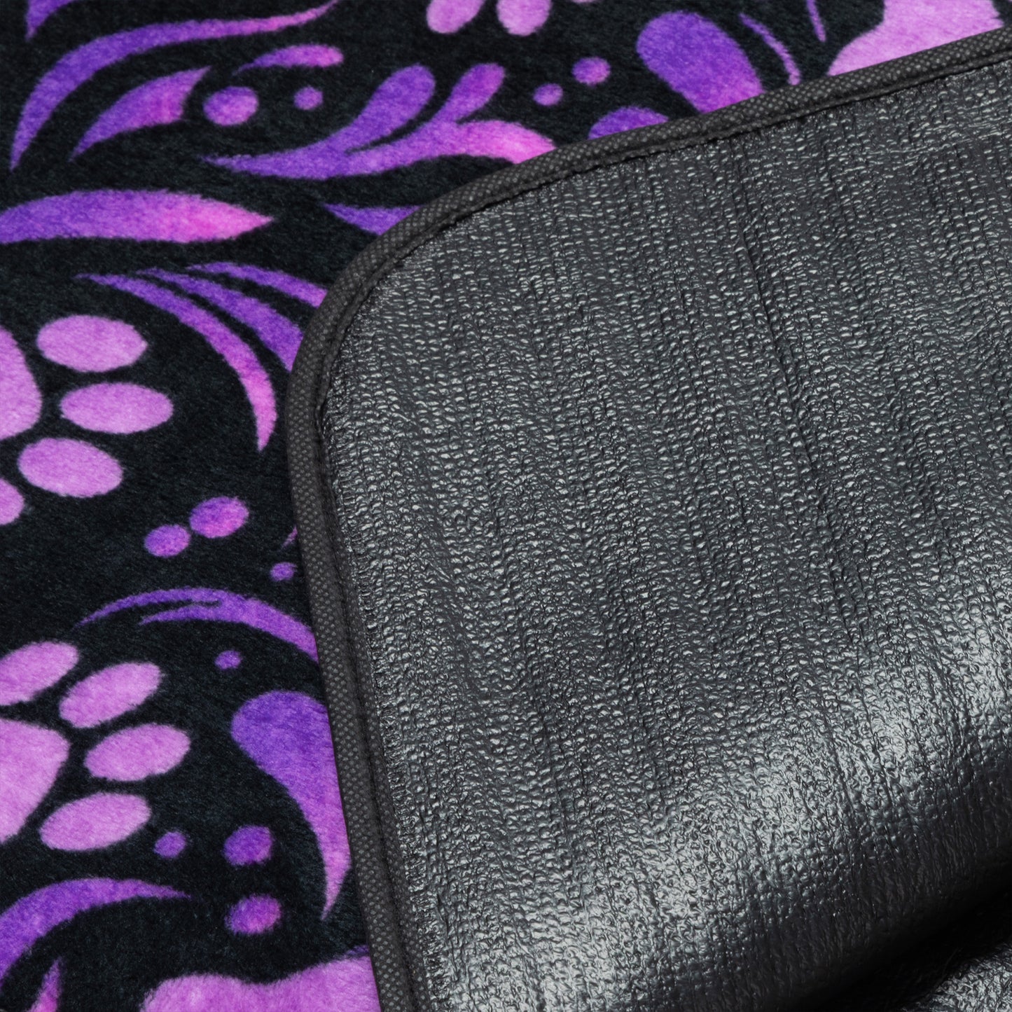 Black textured waterproof backing on a purple and black patterned fleece blanket.
