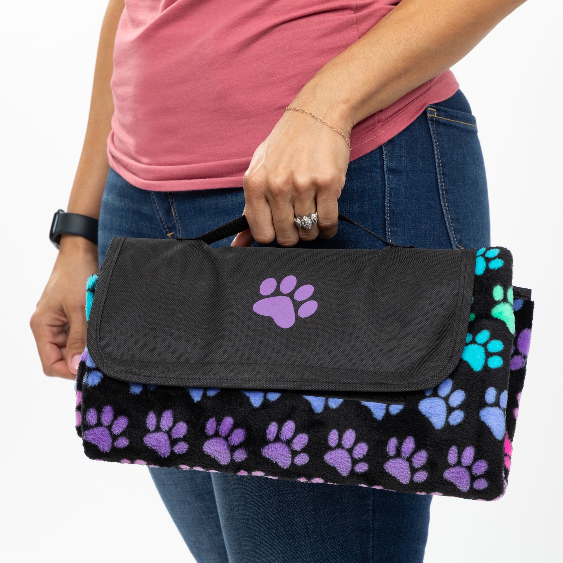 Person holding a packable blanket with paw prints on a colorful paw pattern.
