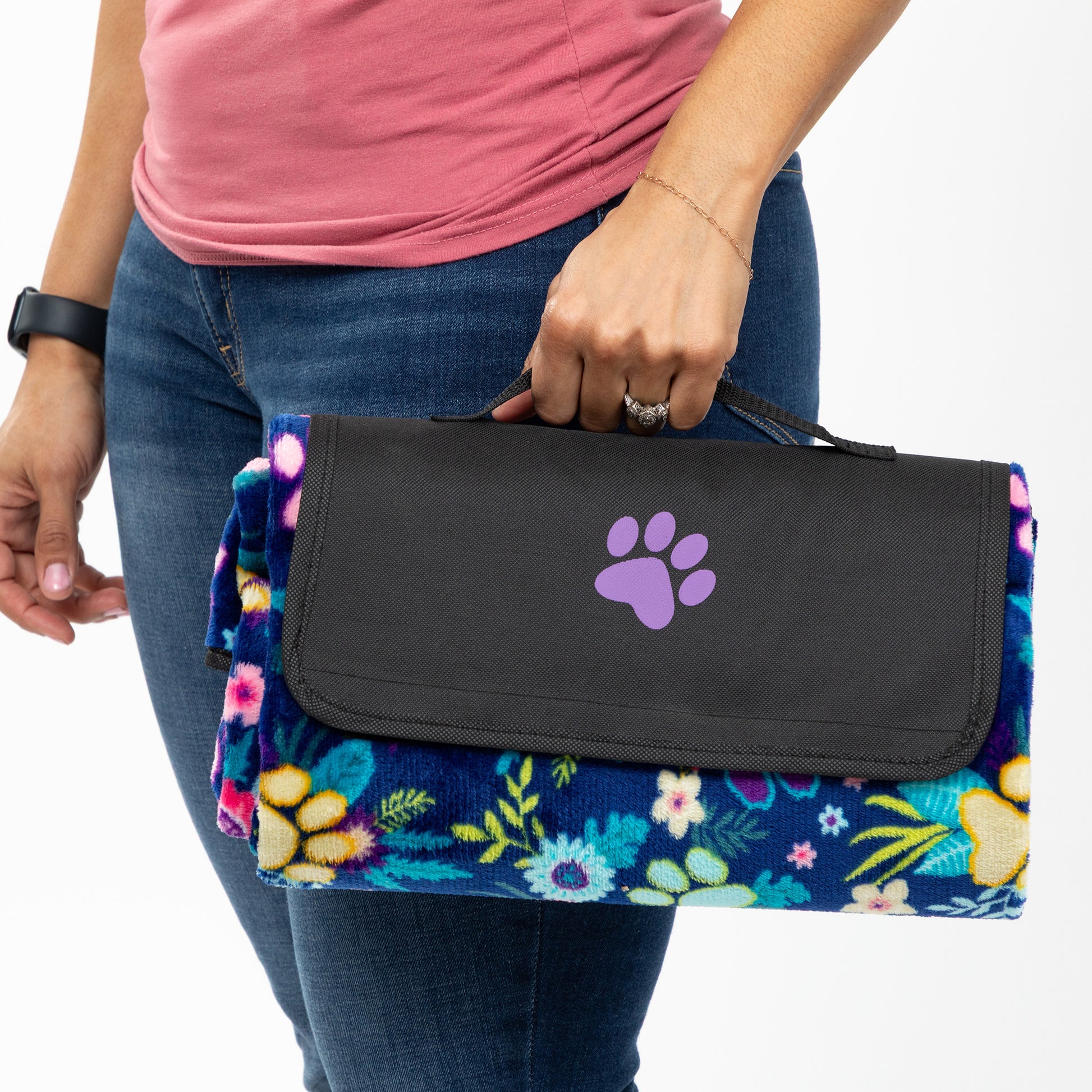 Person holding a floral-patterned pet blanket with a purple paw print design.