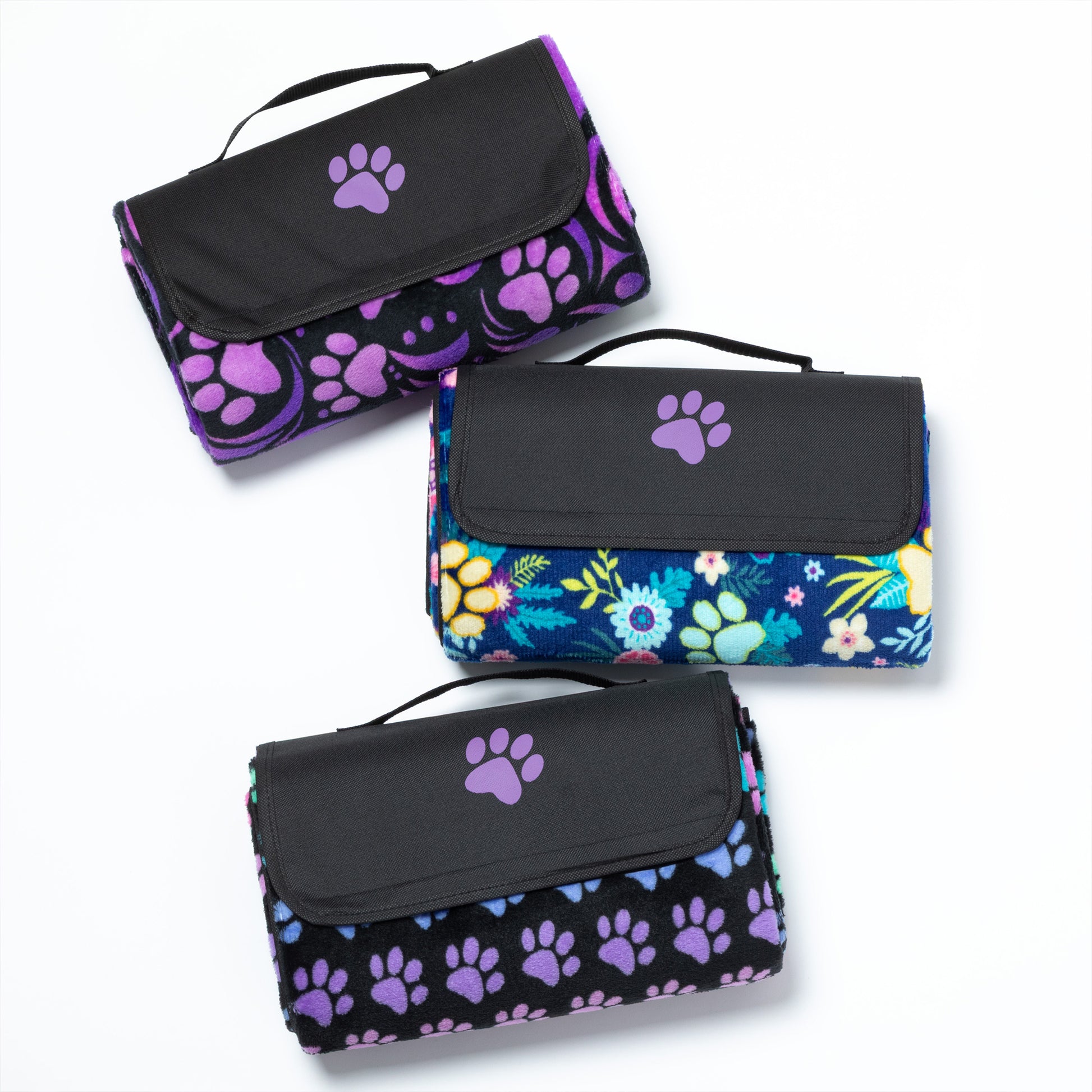 Three folded picnic blankets with paw print and floral patterns on a white background