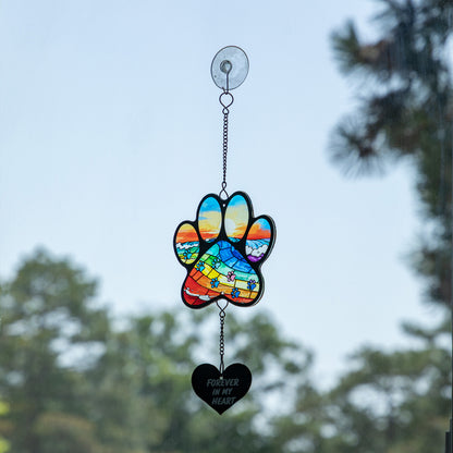 Rainbow bridge stained glass sun catcher with a heart that says "forever in my heart" hanging on a glass window.
