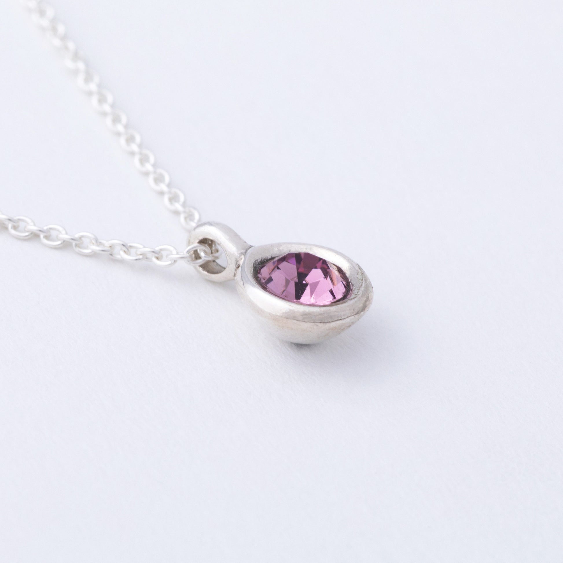 Necklace with a teardrop-shaped pink gemstone on a white background