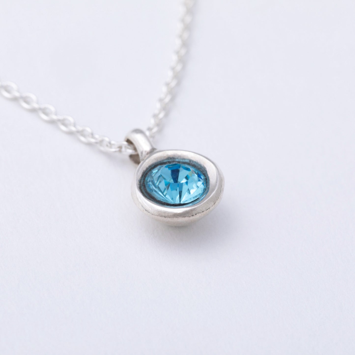 Silver necklace with a blue gemstone on a white background