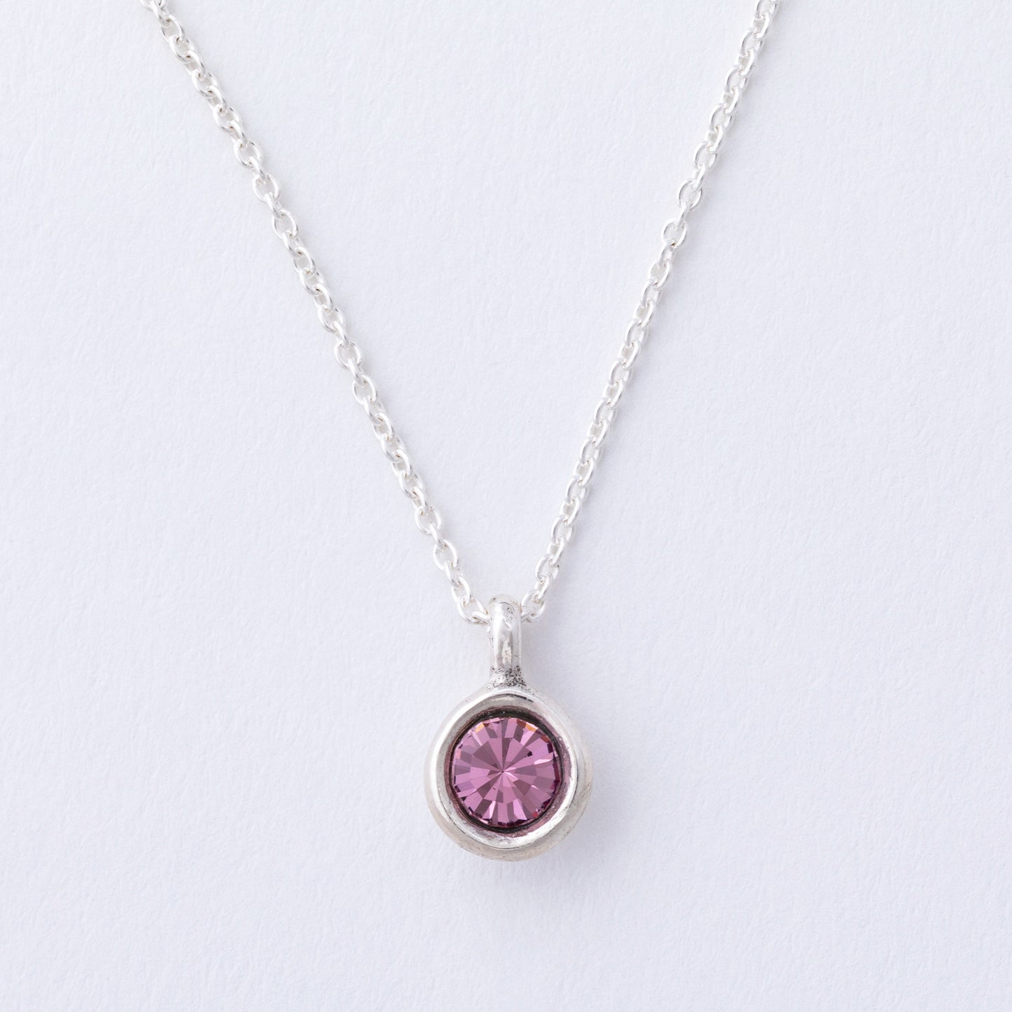Silver necklace with a pink gemstone pendant on a light gray background