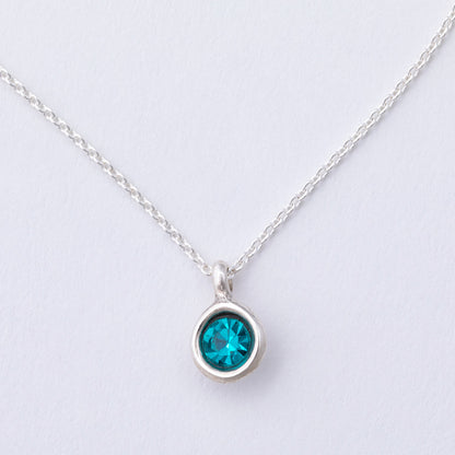 Silver necklace with a blue gemstone pendant on a light gray background