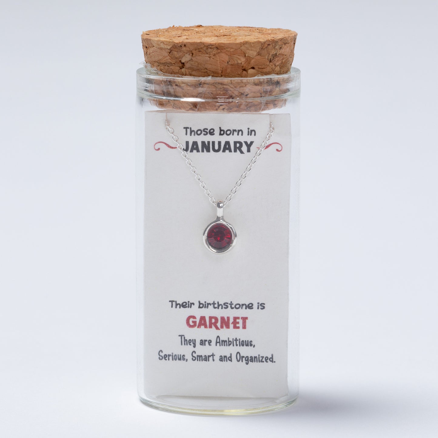 Glass jar with a necklace inside, featuring a message and birthstone information.