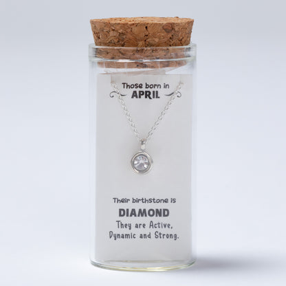 Silver necklace in a glass jar with cork lid on a white background