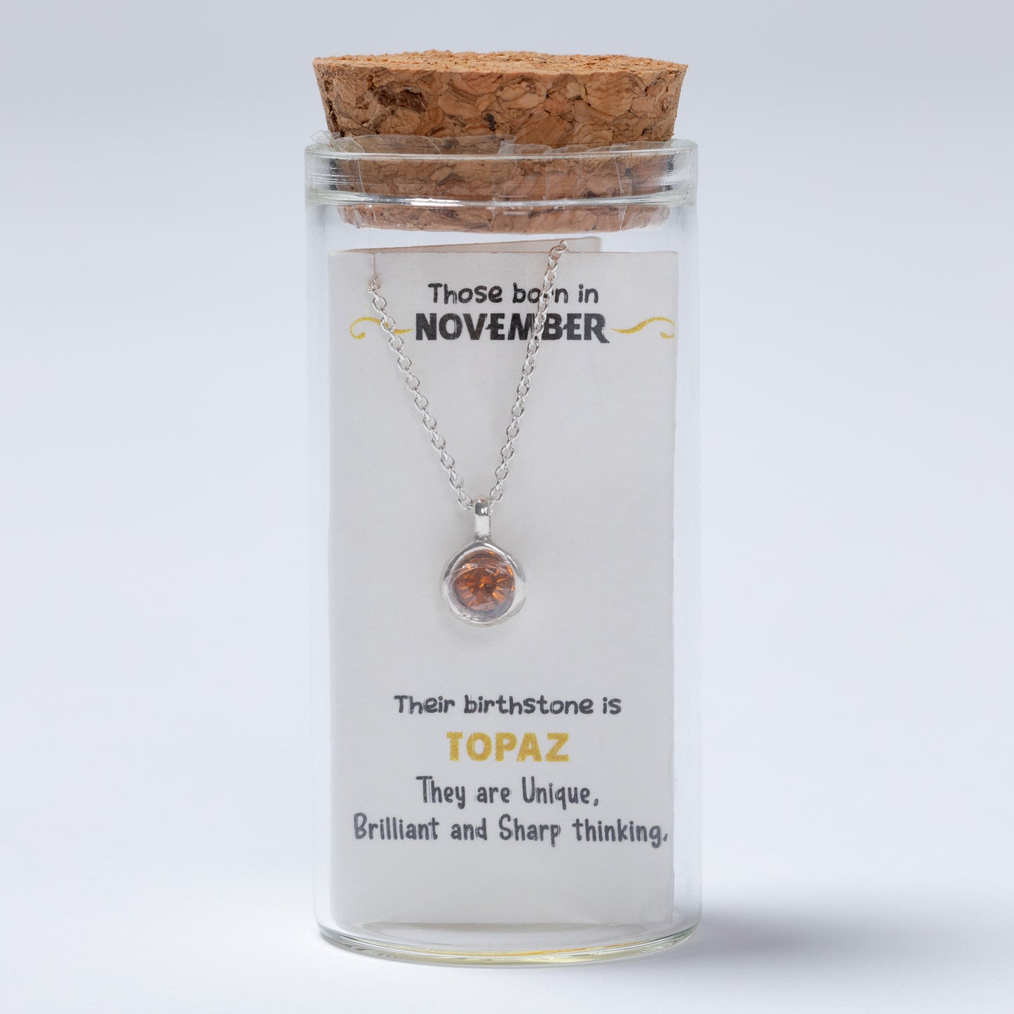 Necklace in a glass jar with cork lid, featuring text about November birthstones on a white background