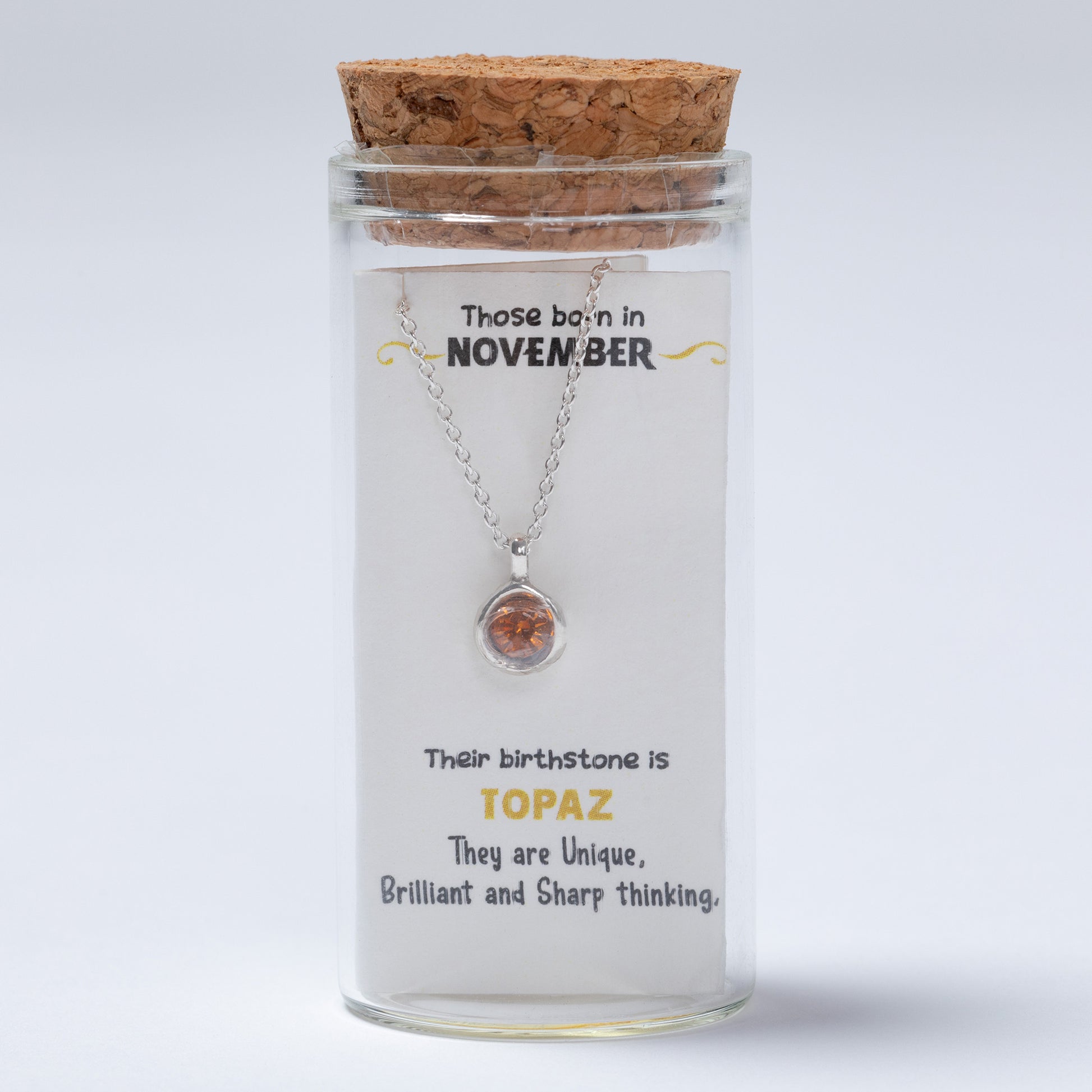 Necklace in a glass jar with cork lid, featuring text about November birthstones on a white background