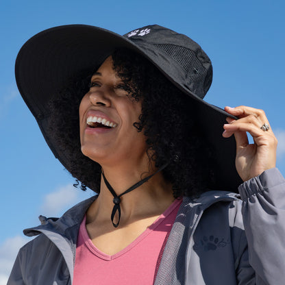 Woman wearing a wide-brimmed black hat against a blue sky