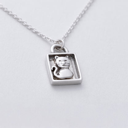 Silver pendant with a cat design on a white background