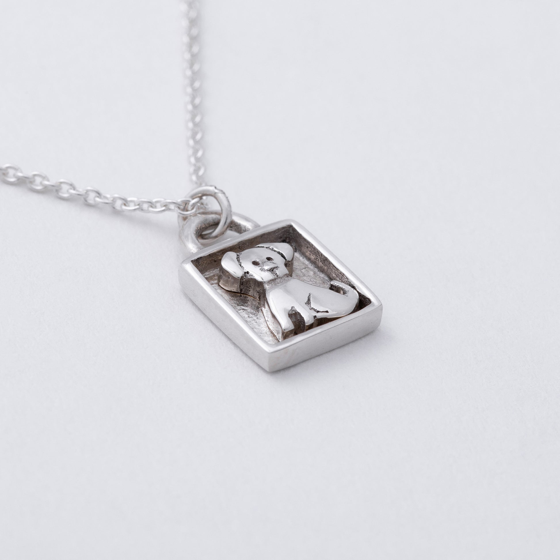 Silver pendant with a dog design on a white background