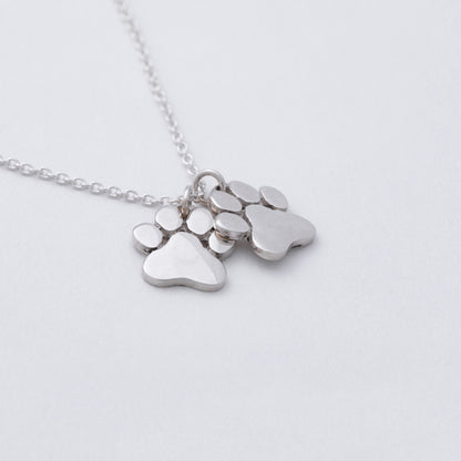 Silver necklace with paw-shaped pendants on a light gray background