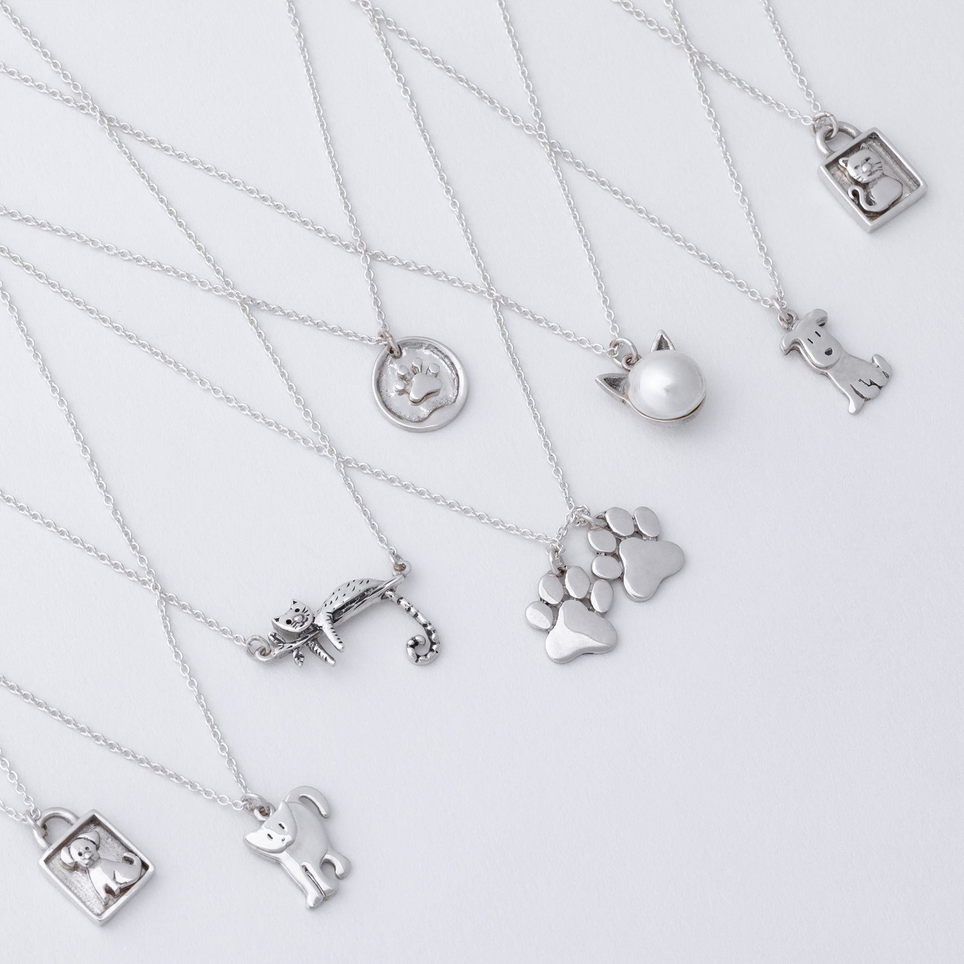Collection of silver necklaces with various pendants on a light gray background