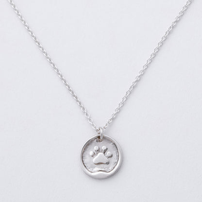 Silver necklace with a paw print pendant on a light gray background
