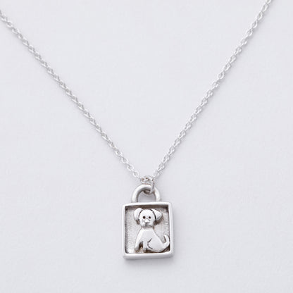 Silver necklace with a pendant featuring a dog design on a light gray background