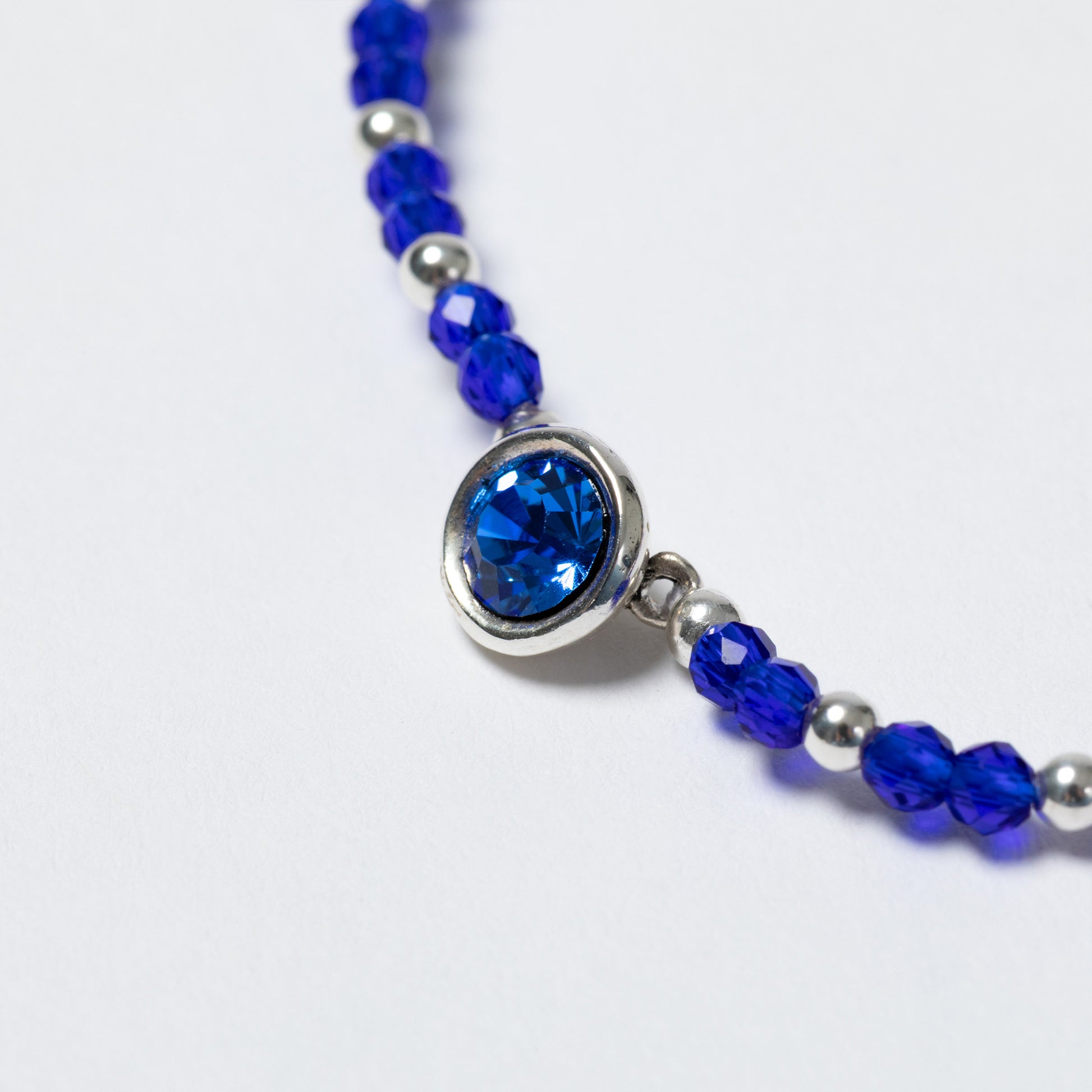 Bracelet with blue beads and a silver clasp on a white background