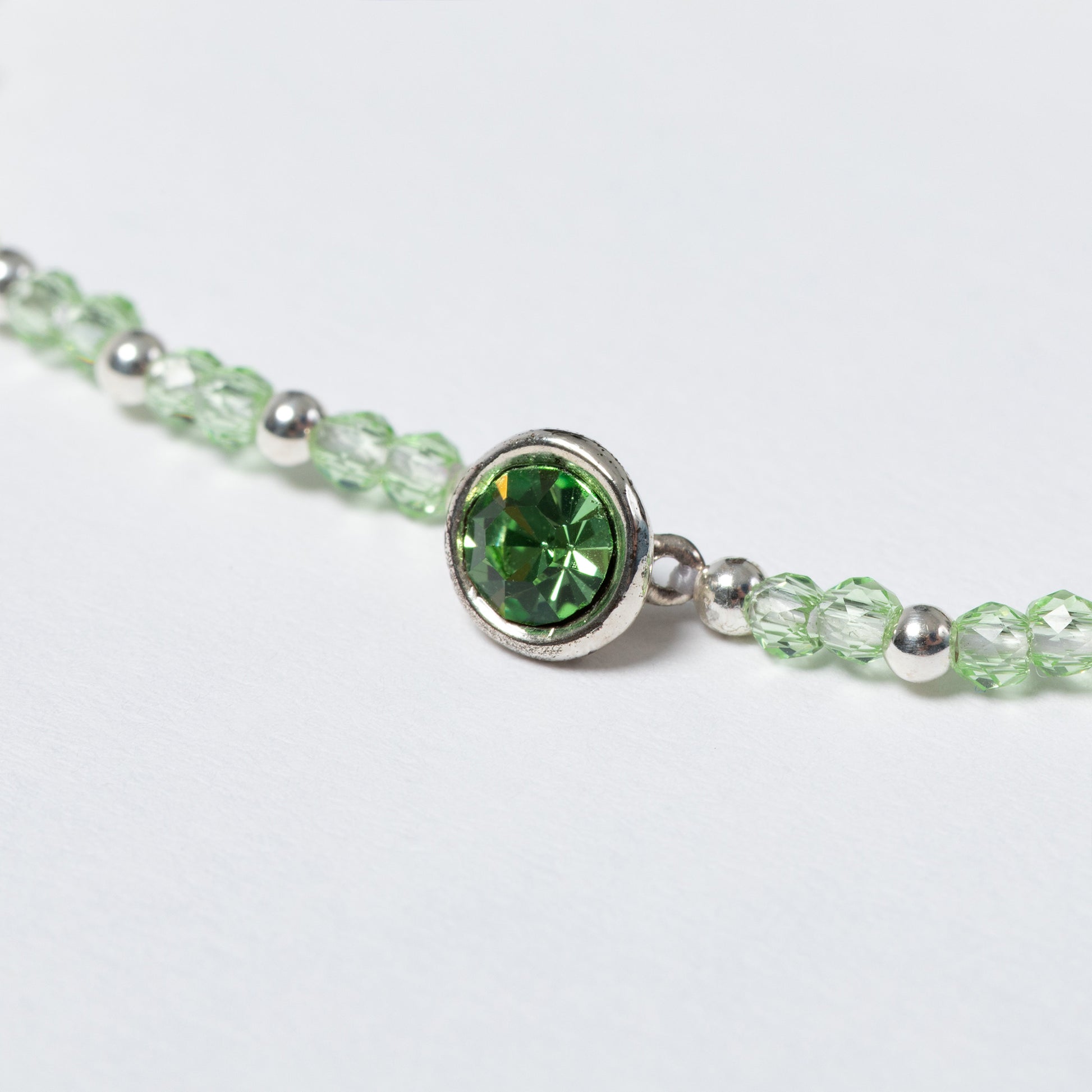 Close-up of a bracelet with a green gemstone on a light gray background