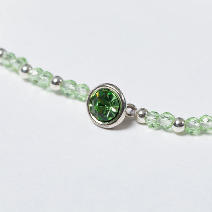 Close-up of a bracelet with a green gemstone on a light gray background