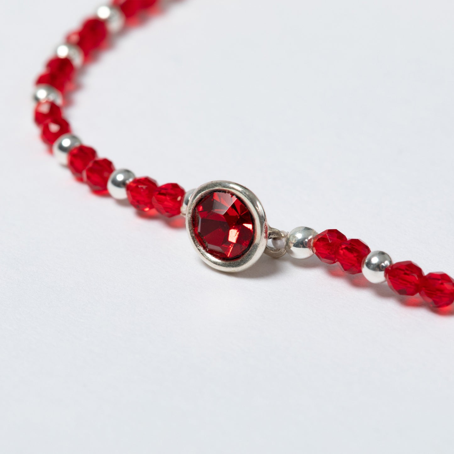 Bracelet with red beads and a silver clasp on a white background