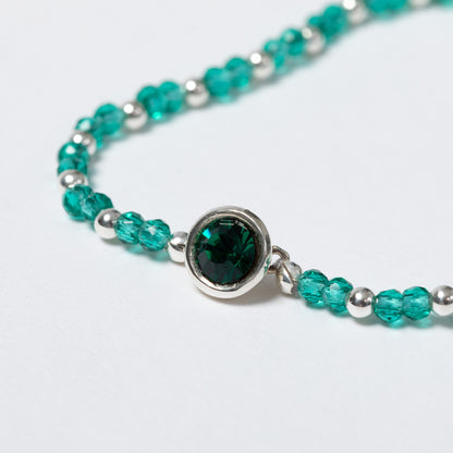 Bracelet with green gemstone and silver beads on a light gray background