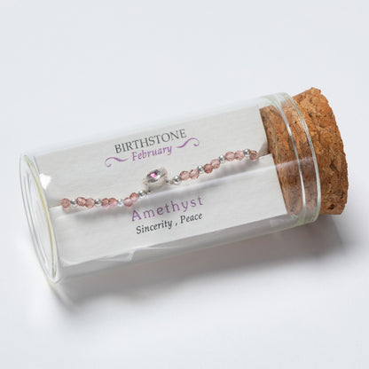 Amethyst bracelet in a glass tube with cork lid on a white background