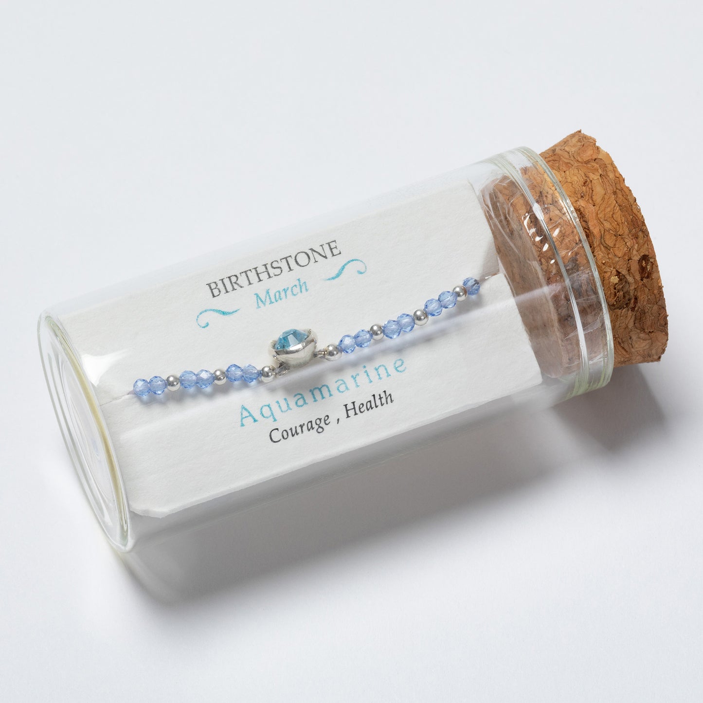 Aquamarine bracelet in a glass jar with cork lid on a white background
