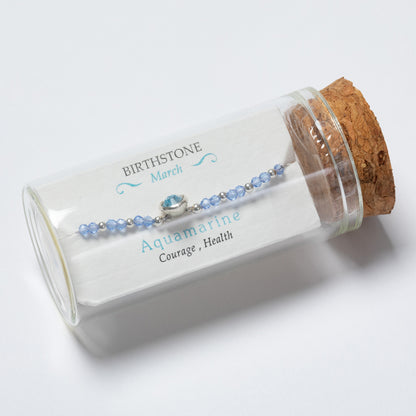 Aquamarine bracelet in a glass jar with cork lid on a white background