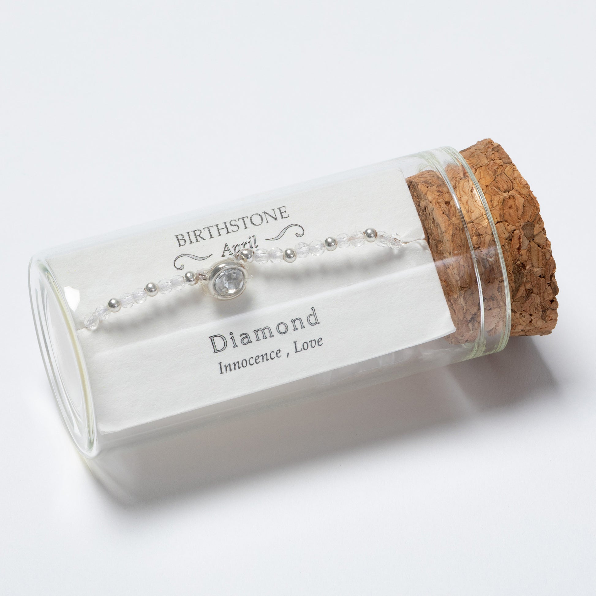 Glass jar with cork lid containing a diamond necklace on a white background