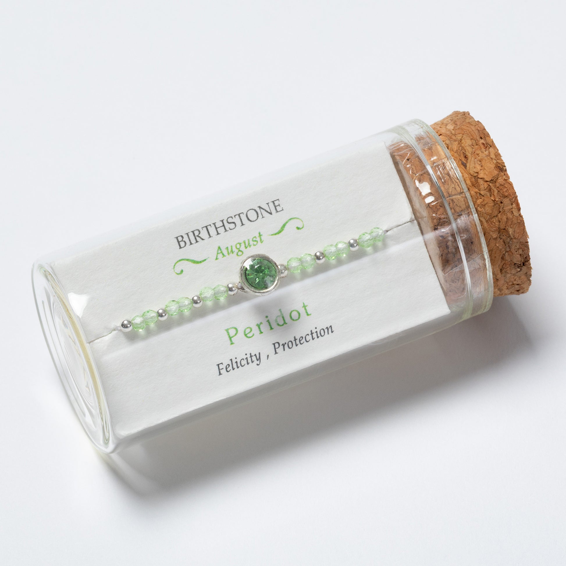 Green beaded bracelet in a glass jar with cork lid on a white background