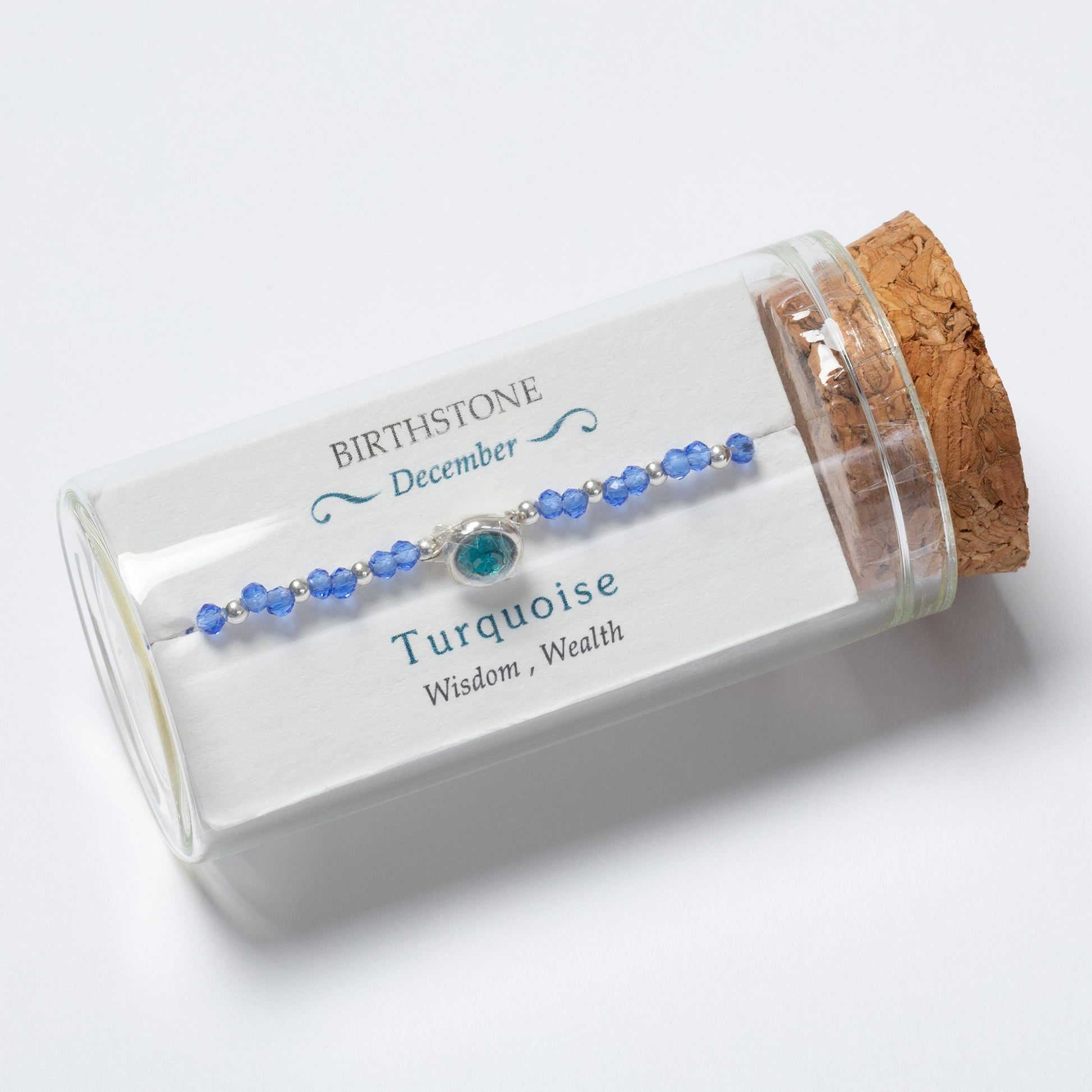 Turquoise beaded bracelet in a clear glass jar with cork lid on a white background