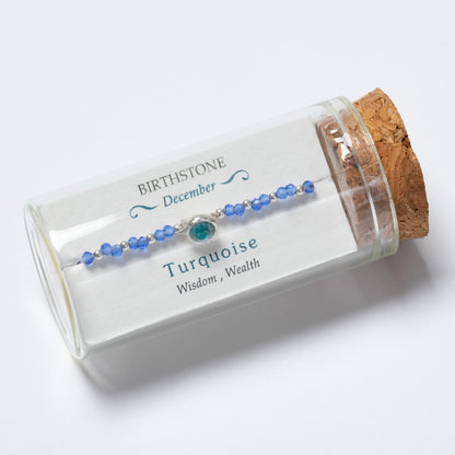 Turquoise beaded bracelet in a clear glass jar with cork lid on a white background