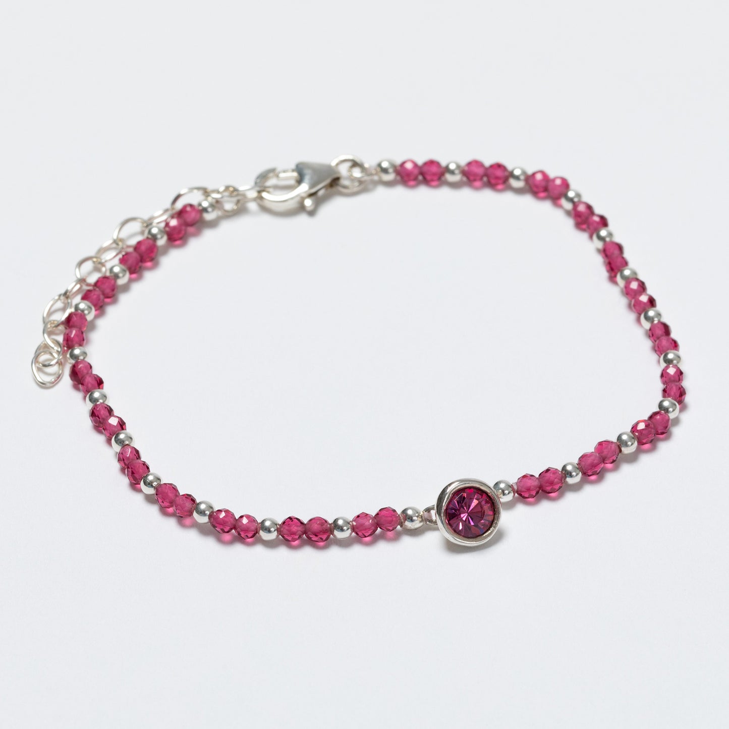 Bracelet with pink beads and a silver clasp on a light gray background