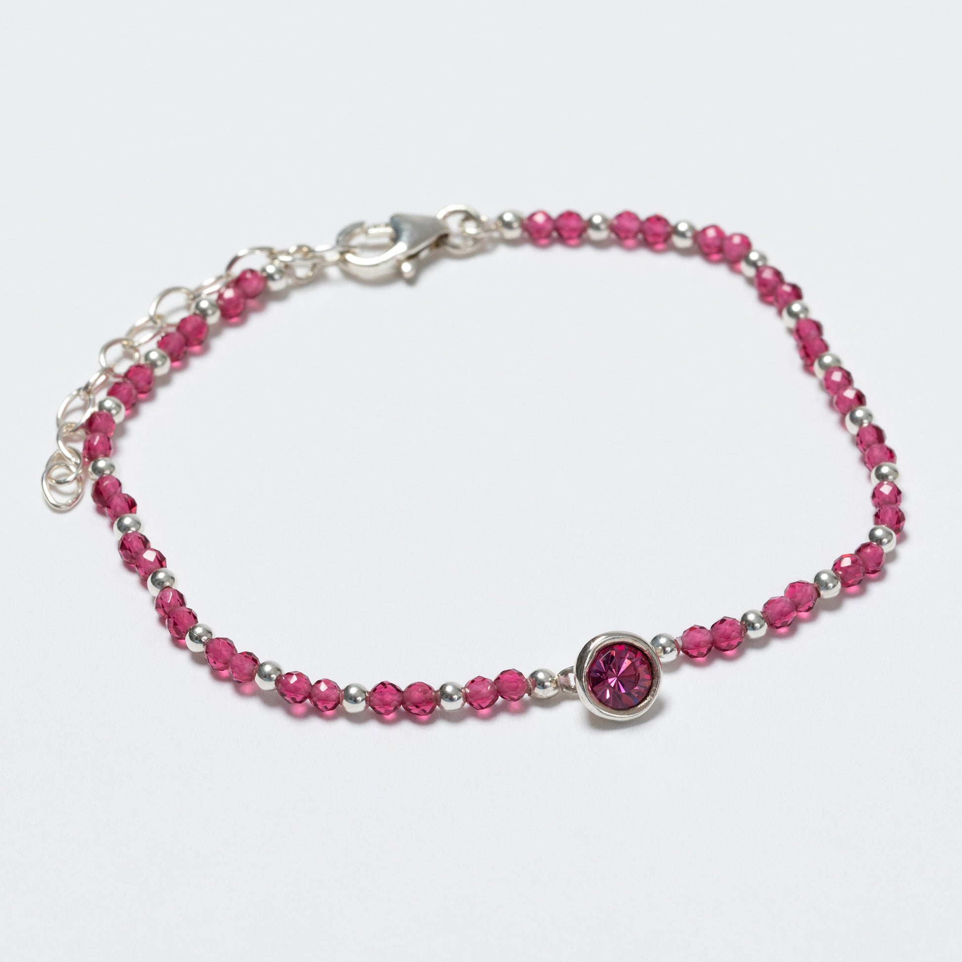 Bracelet with pink beads and a silver clasp on a light gray background