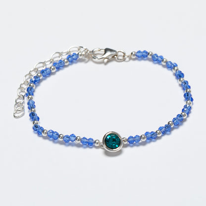 Blue beaded bracelet with a silver clasp on a white background