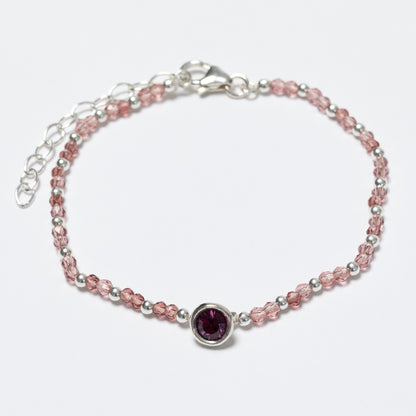 Bracelet with pink beads and a purple gemstone on a white background