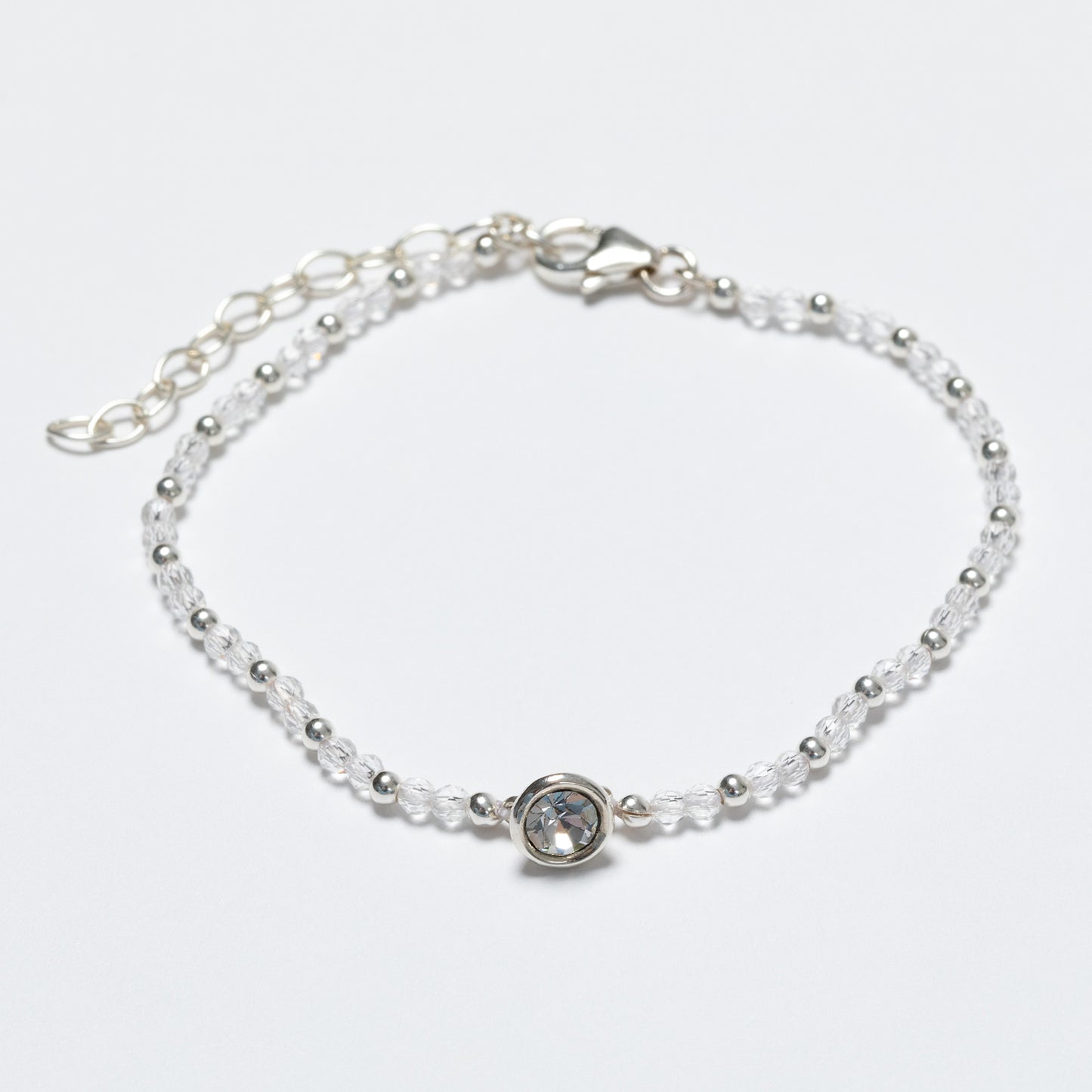 Silver bracelet with a clear gemstone on a light gray background