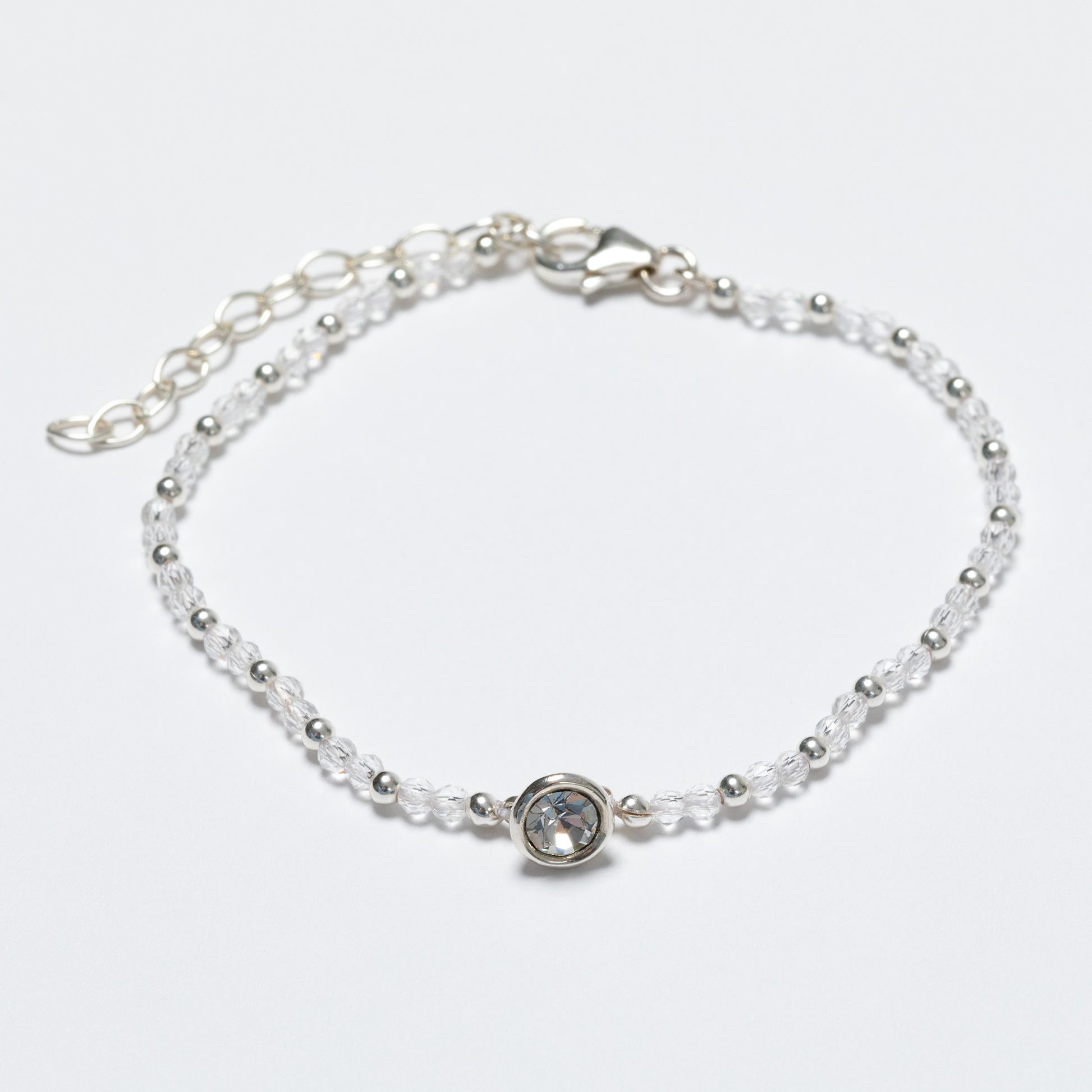 Silver bracelet with a clear gemstone on a light gray background