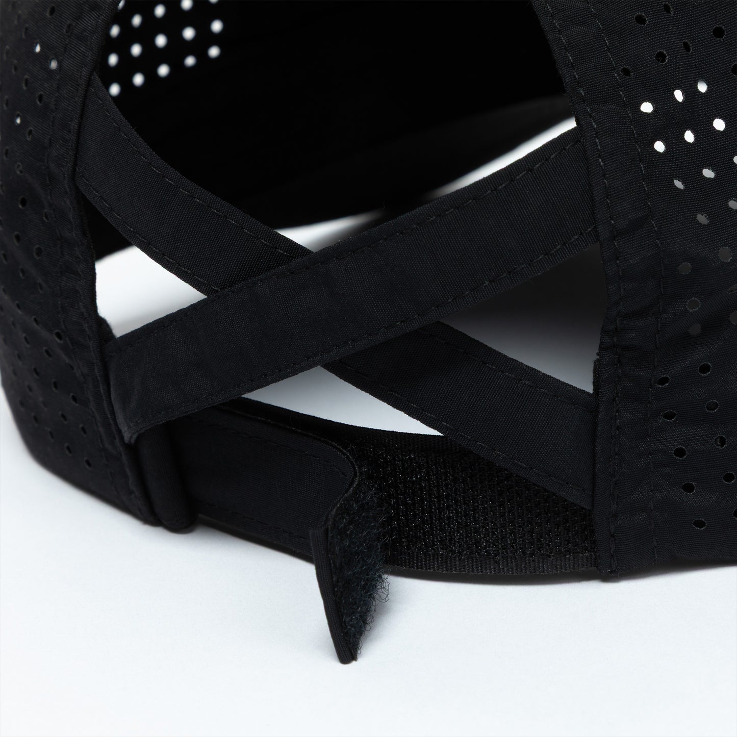 Black cap with perforated design and ponytail opening on a white background