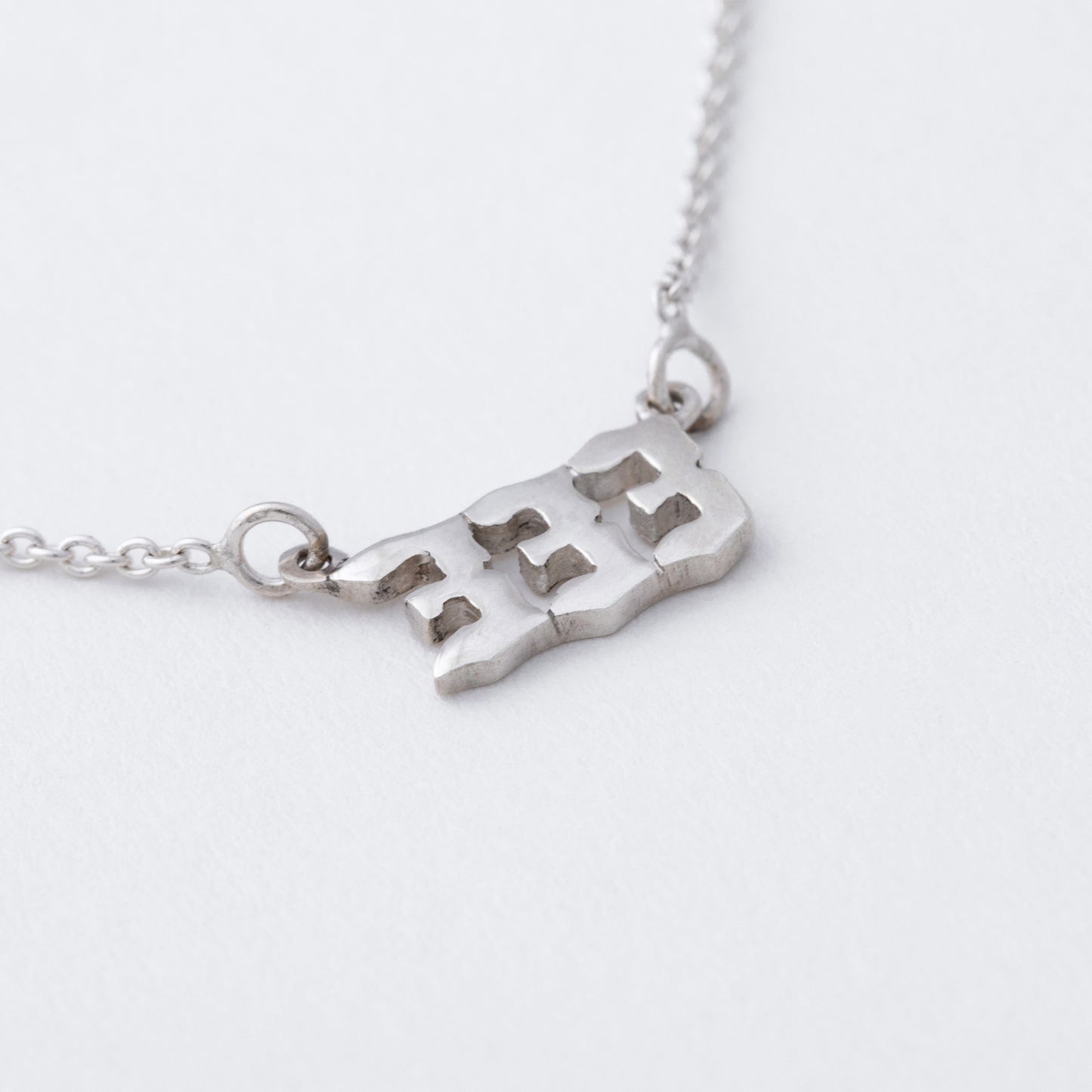 Silver necklace with a map pendant on a white background