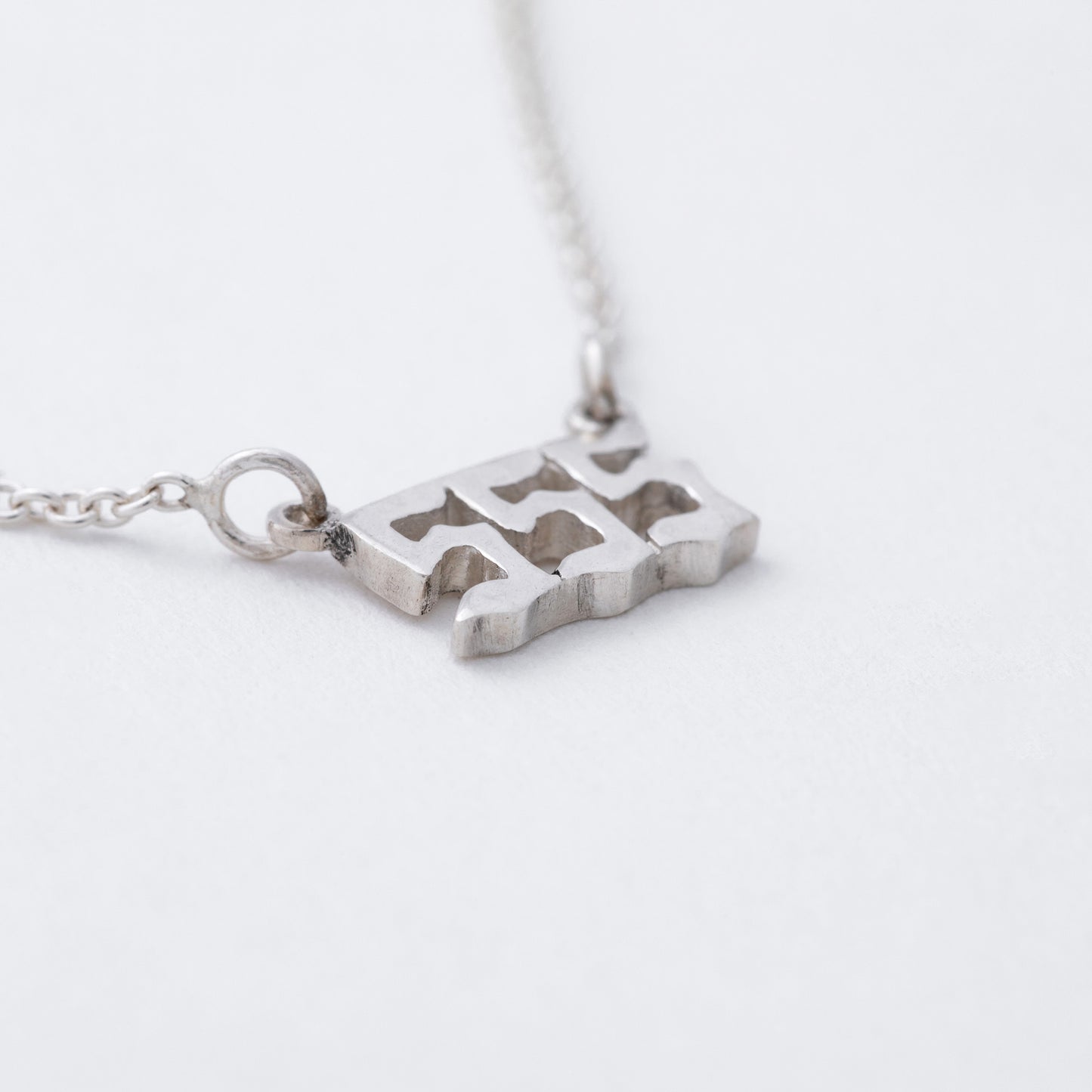 Silver necklace with a unique pendant on a light gray background