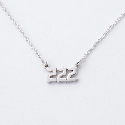 Silver necklace with the number '222' on a white background