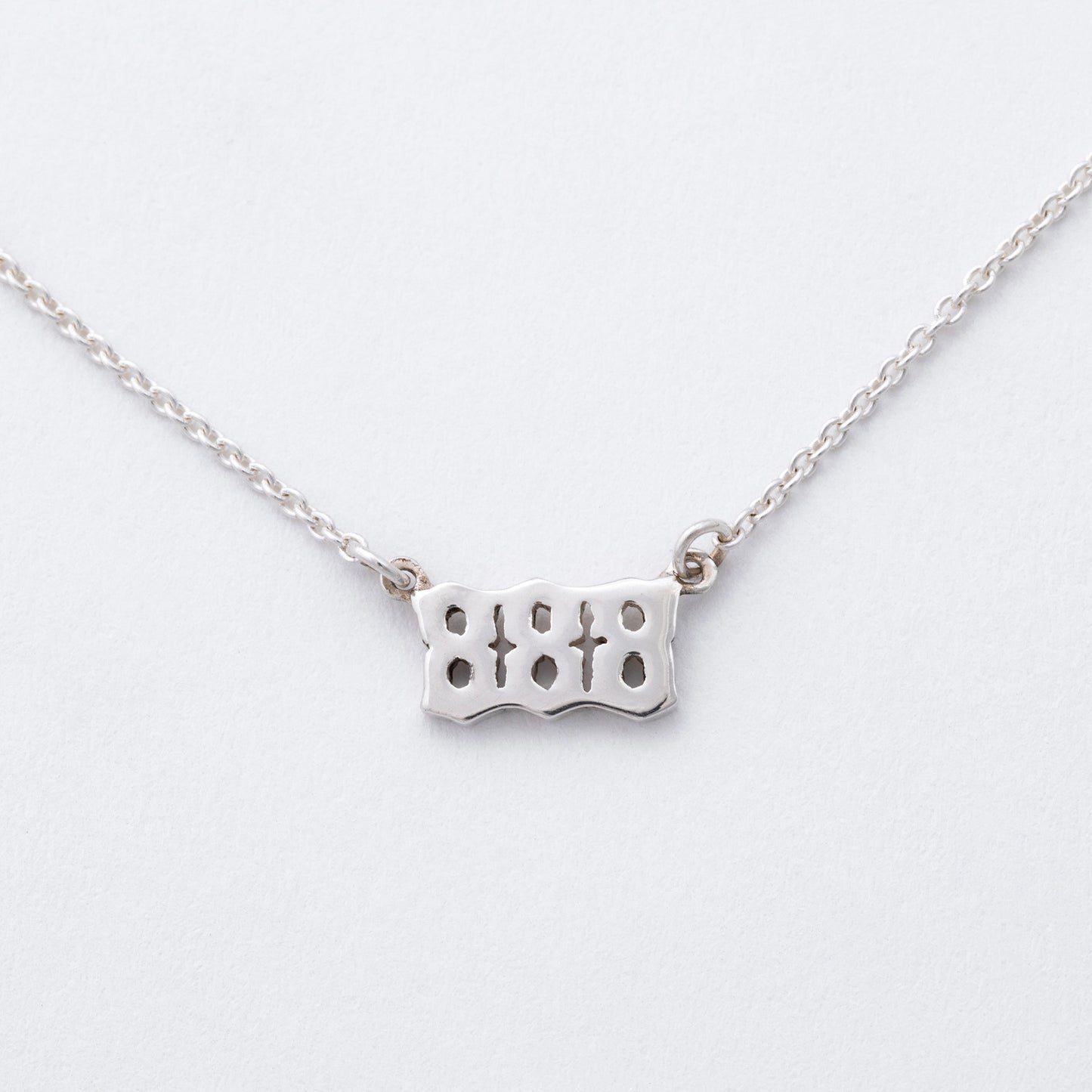 Silver necklace with a unique pendant on a light gray background
