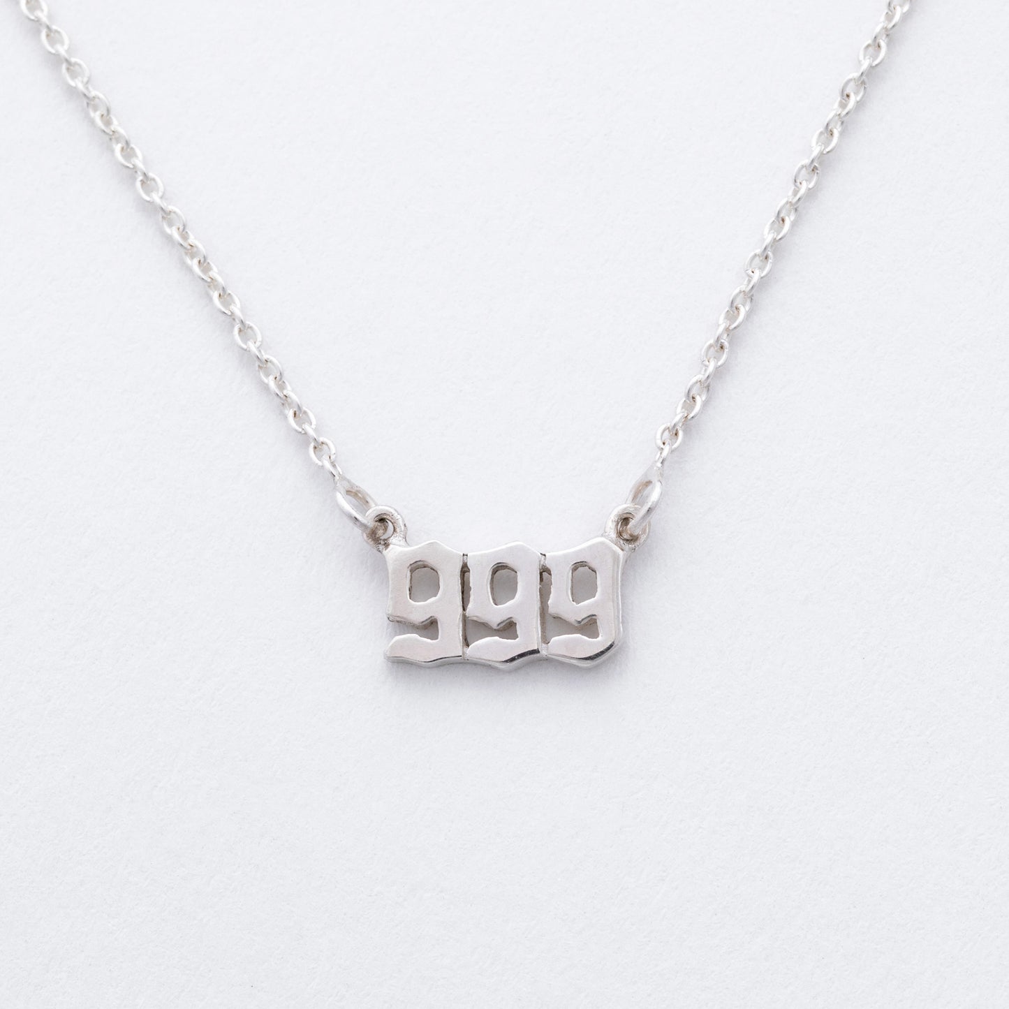Silver necklace with '999' pendant on a white background