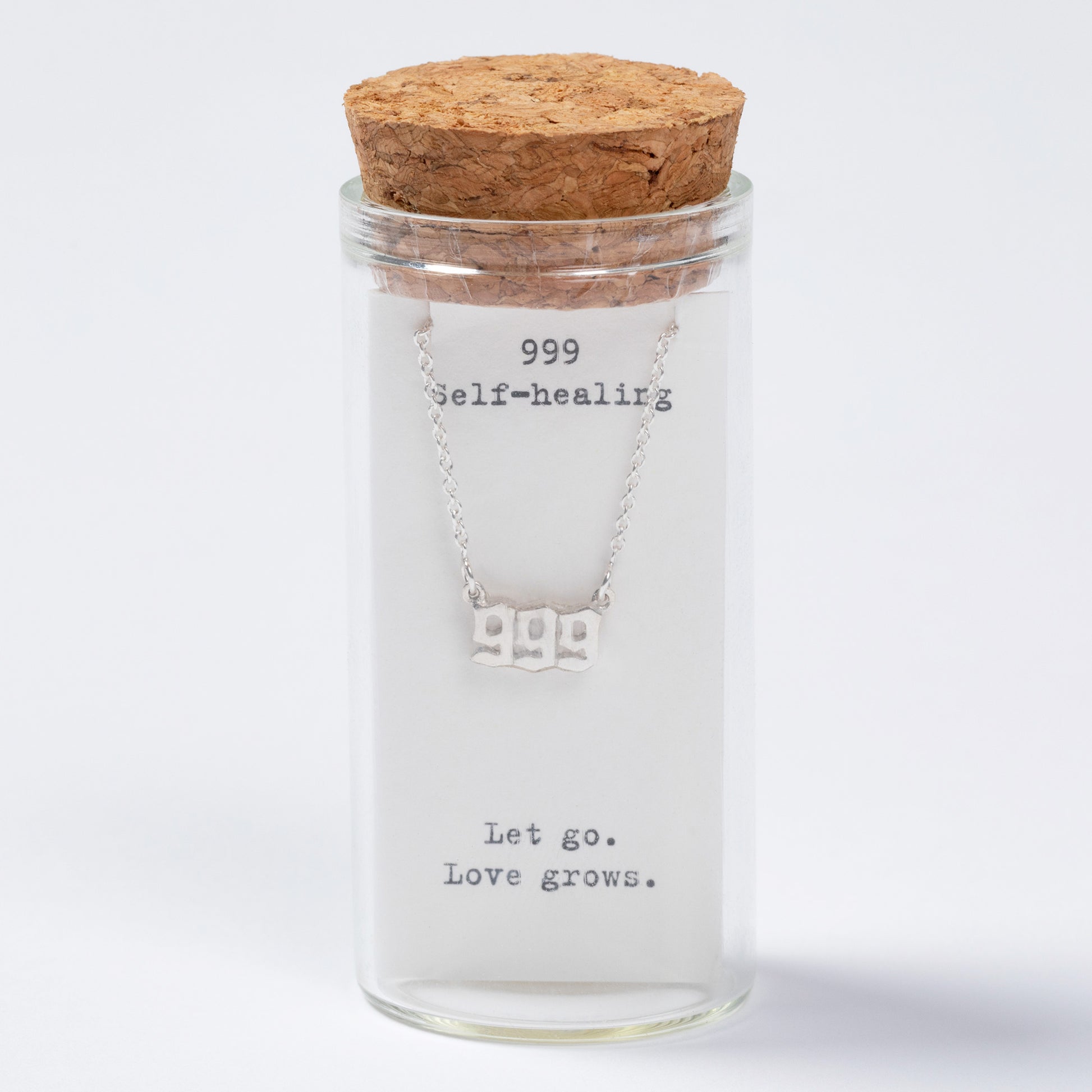 Necklace in a glass jar with cork lid on a white background